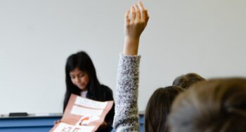 person raising their hand in class